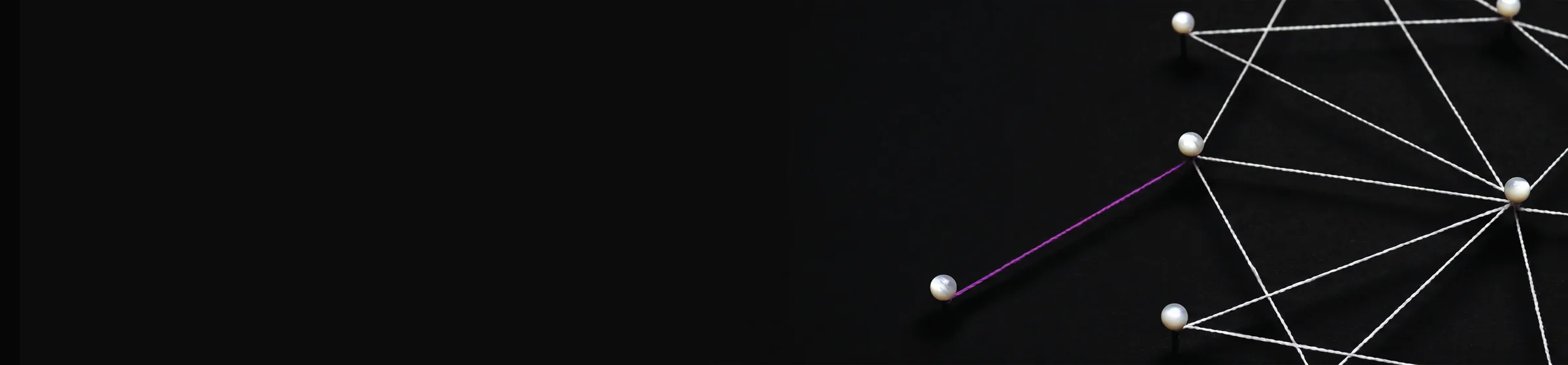 Rete di fili tesi tra spilli su fondo nero